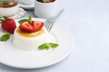 Tasty panna cotta with caramel, strawberries and mint on light table, closeup. Space for text