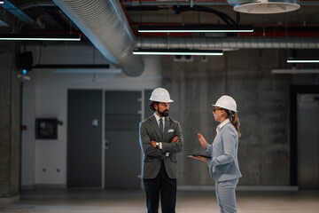 Architects discussing building plans during construction in unfinished office space