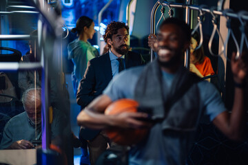 Passengers riding on a bus at night, diverse people using public transport