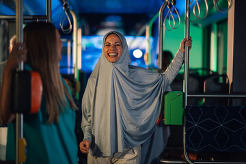 Muslim woman wearing hijab smiling while riding bus