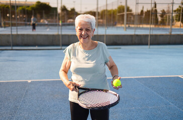 Senior woman playing tennis on a sunny day, active retirement and healthy lifestyle