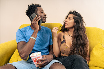 A woman looks annoyed and impatient while her partner talks on the phone, ignoring her at home.