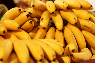 Ripe bananas piled up. Yellow bananas sold in supermarket. Food. Grocery background. Bunch of ripe bananas at street market. Mini or baby bananas close up