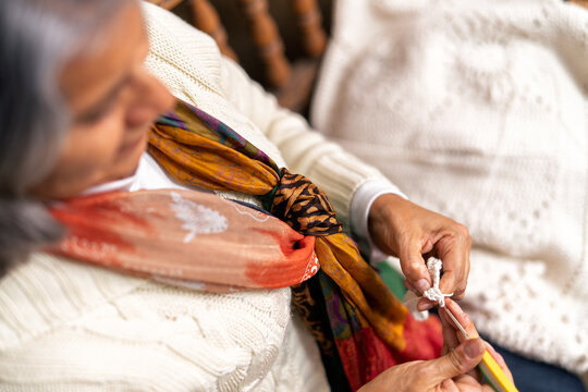 Senior woman knitting with crochet hook and yarn in backyard - Powered by Adobe