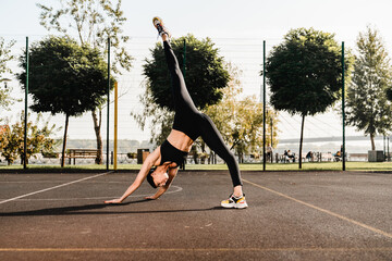 Fitness routine concept. Portrait of determined young Caucasian woman stretching leg doing yoga...