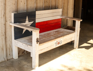 Texas themed wooden bench on the porch with Texas Flag painted on the back and a bottle opener on one of the legs.
