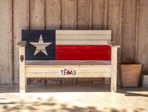 Texas themed wooden bench on the porch with Texas Flag painted on the back and a bottle opener on one of the legs.