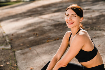 Close up of strong athlete rests between workouts, sitting relaxed on the steps. Fitness girl...