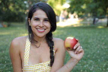 Healthy looking woman eating an apple in the park 
