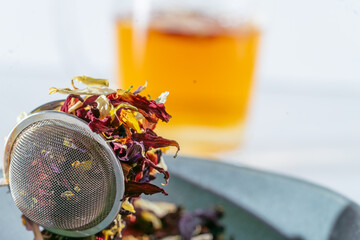 colorful dried flower petals filled in a tea-egg tongs and blue bowl, tea concept, close up, macro