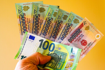 Vietnam dong and euro banknotes, held in hands, yellow background, equivalent international exchange