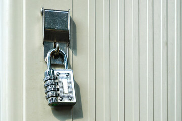 Close-Up of Metal Combination Padlock Securing a Beige Door with Vertical Panel Pattern