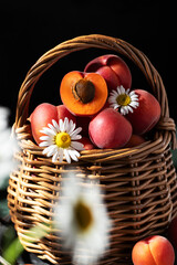 Close up of ripe yellow and red apricots in a wicker basket decorated with daisies. Summer mood. Seasonal fruits. Rustic style