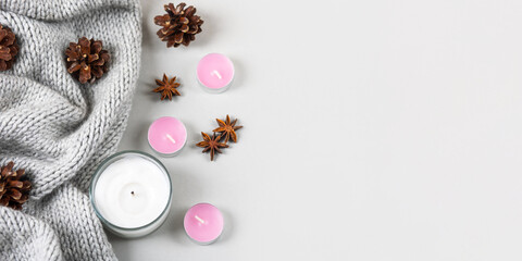 Winter cozy composition of knitted sweaters, candles, pine cones, stars of star anise.