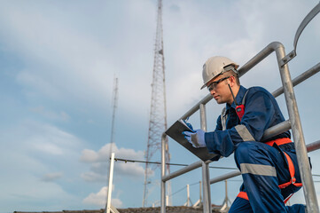 Engineer in Full Safety Gear Climbing a Ladder to Inspect Communication Signals and Industrial...