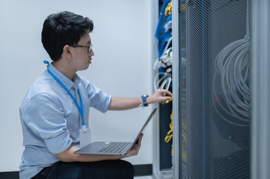 Computer engineer is setting up network in server room,Systems Maintenance Technician,Male engineer working in server room at modern data center