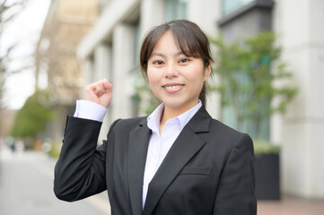 ビル街でガッツポーズをする日本人女性