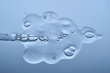 The beautiful texture of the hyaluronic serum with a pipette on a blue background.
