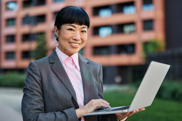 Portrait of a young asian japanese businesswoman woman using a laptop computer and sitting on a...