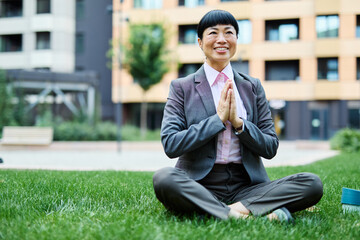 Portrait of a young asian japanese businesswoman woman practicing yoga outdoors, surrounded by...