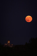 Illuminated church tower, reddish full moon.