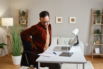 Man at desk holding back, showing discomfort