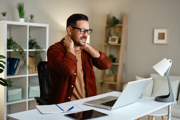 Man experiencing neck pain while working at desk