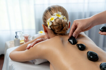 Hot stone massage at spa salon in luxury resort with day light serenity ambient, blissful woman...