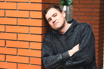 Man Leaning Against Brick Pillar in Urban Setting During Daytime Deep in Thought