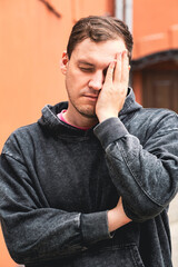Obraz premium Man Expressing Frustration While Leaning Against His Hand in a Casual Setting During Daylight