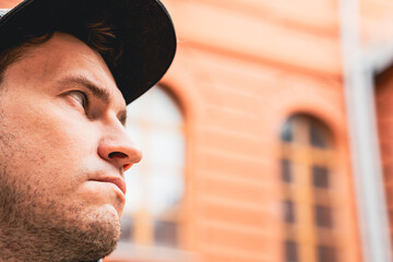 A man stands with a pensive expression on his face gazing upwards against a backdrop of an orange...
