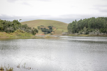 Foto de uma ponte cruzando uma represa em meio à natureza. As águas calmas refletem a estrutura e a vegetação ao redor, compondo uma cena tranquila e harmônica. Ideal para temas de infraestrutura, mei
