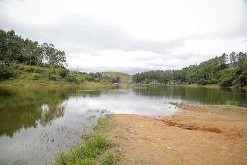 Foto de uma ponte cruzando uma represa em meio à natureza. As águas calmas refletem a estrutura e a vegetação ao redor, compondo uma cena tranquila e harmônica. Ideal para temas de infraestrutura, mei