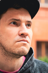In an urban setting a young man stands confidently against a red brick building He wears a casual...