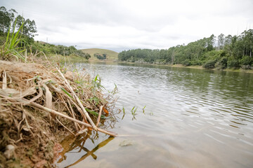 Foto de uma ponte cruzando uma represa em meio à natureza. As águas calmas refletem a estrutura e a vegetação ao redor, compondo uma cena tranquila e harmônica. Ideal para temas de infraestrutura, mei