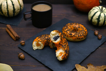 orange donuts, coffee, pumpkins and autumn leaves on a wooden background