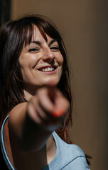 Smiling young caucasian female pointing forward in bright sunlight
