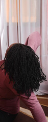 Plussize woman doing yoga stretches in her home, brown skin woman stretching to keep fit