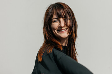 Smiling caucasian female adult with brown hair against plain background