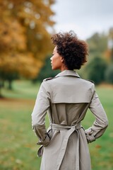 Stylish Woman Walking Alone in Autumn Park Wearing a Beige Trench Coat