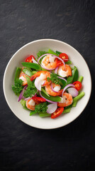 A vibrant shrimp salad with fresh snap peas, red onion slices, and juicy tomatoes is artfully arranged in a white bowl against a dark textured background.