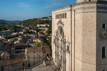 The impressive stone facade of Girona Cathedral rises under a clear blue sky, with its intricate...