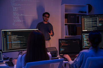 Asian man presents code using a projector during a software development meeting or coding workshop,...