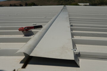 Installation of a specialized ridge cap designed specifically for industrial white sandwich panels....