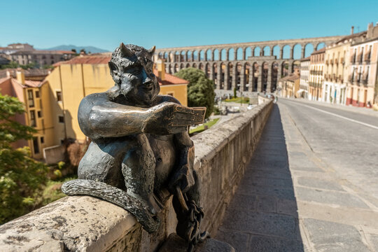 View of the Estatua del Diablo, a bronze statue of a smiling devil taking a selfie photo of itself sited in the city of Segovia Spain