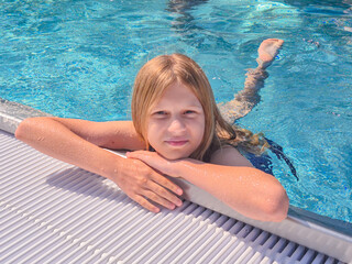 A child is joyfully swimming in a refreshing pool under the bright sunlight shining down