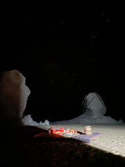 A peaceful night scene in Egypt’s White Desert, featuring rock formations, glowing lights from a...