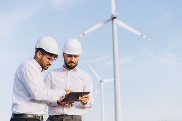 Engineers using tablet working on wind turbine farm
