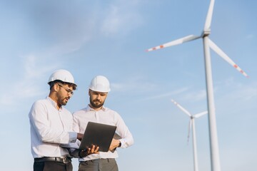 Engineers using laptop analyzing wind turbine operation