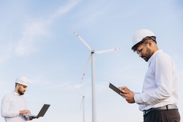 Engineers working in a wind turbine power plant using laptop and tablet